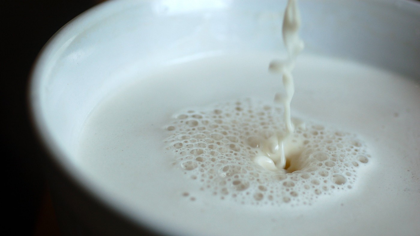Raw oat milk being poured into a container.